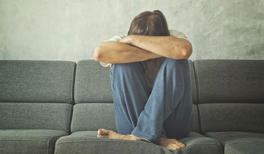 imageof a man on a couch suffering from mental health issues