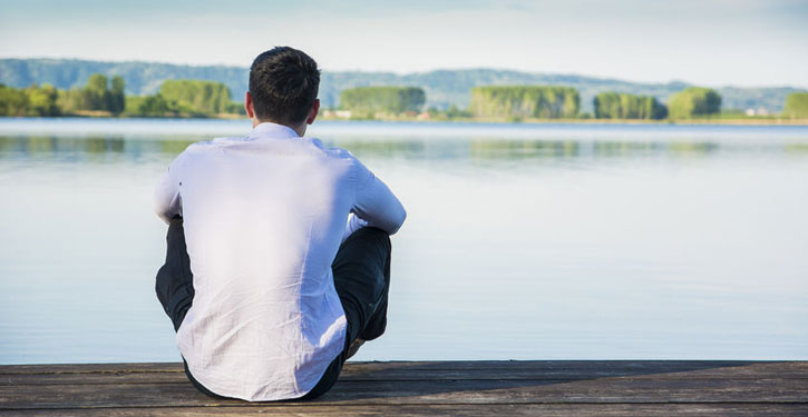 Image of man sitting on a dock thinking about trauma therapy